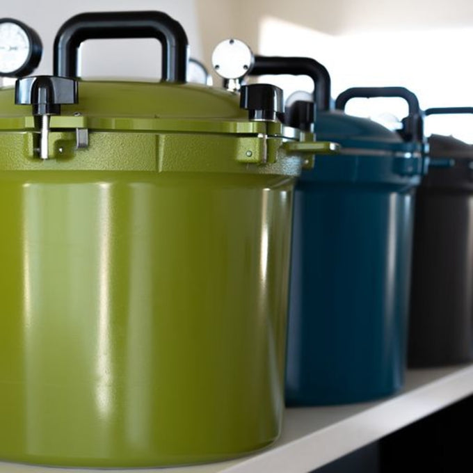 Row of handcrafted pressure canners in vibrant green, blue, and black with locking lids and built-in gauges, made in USA for Kitchen & Food, Canning, Food Preservation, and Best Sellers collections.