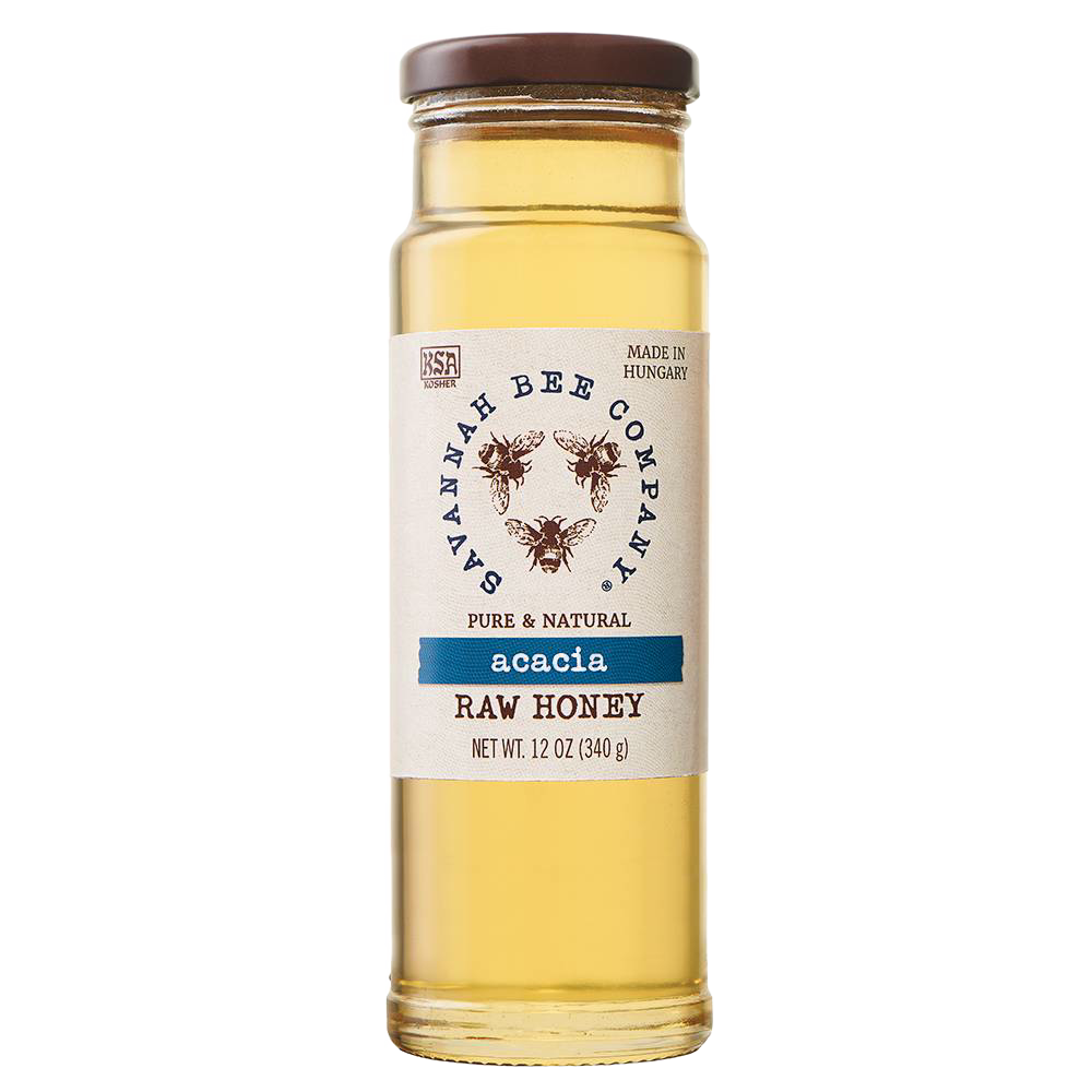 Clear glass jar of golden acacia raw honey with a simple white label featuring bee illustrations, sealed with a brown lid, ideal for kitchen and food pantry use.
