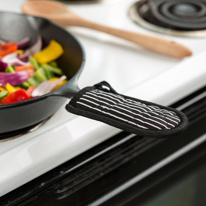 Black and white striped padded handle cover securely fitted on a cast iron skillet handle, offering heat protection up to 350°F, featured in Kitchen & Food, Cookware, Cast Iron, and Best Sellers collections.