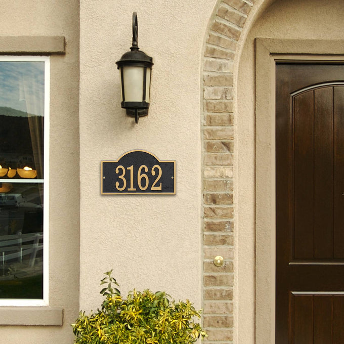 Handcrafted black and gold arched rectangle address plaque mounted on a light stucco wall next to a dark brown front door and outdoor lantern, featured in Home & Decor, Household Helpers, Mailboxes and Address Signs, USA Made, Best Sellers, and Promo Eligible collections.