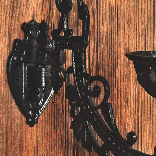 Cast iron wall bracket with ornate Victorian-style scrollwork and a large mounting plate, designed for securely attaching oil lamps, perfect for Lamps & Lighting collections.