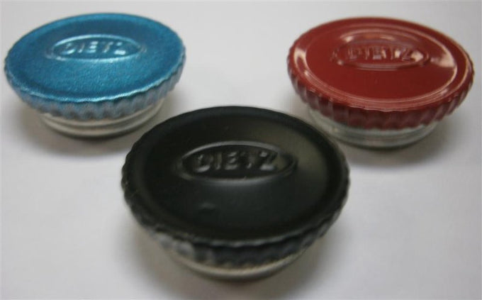 Three black, blue, and red filler caps embossed with a vintage logo, designed for lantern fuel fonts, featured in camping, emergency supplies, and outdoor lighting collections.