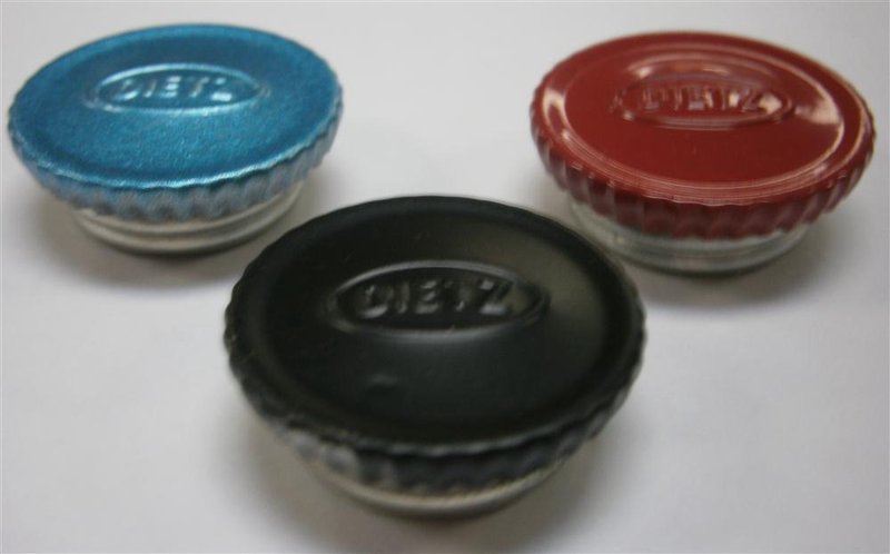 Three black, blue, and red filler caps embossed with a vintage logo, designed for lantern fuel fonts, featured in camping, emergency supplies, and outdoor lighting collections.