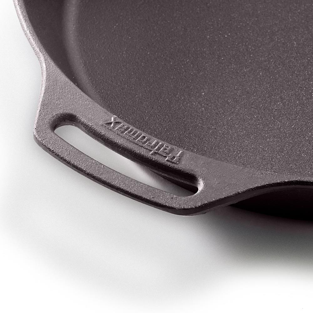 Close-up of a sturdy cast iron skillet’s helper grip with embossed branding, showcasing its smooth cooking surface and durable design for Farm, Garden & Tool, Kitchen & Food, Camping, Cookware, Cast Iron, Best Sellers, and Promo Eligible collections.
