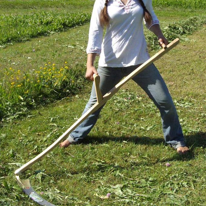Person using a handcrafted Canadian ash snath handle attached to a scythe blade for mowing grass in a green field, ideal for Farm, Garden & Tool, Lawncare, Best Sellers, Promo Eligible collections.