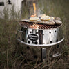 Stainless steel portable camp grill and fire bowl with perforated body and grill top cooking fish with lemon slices, designed for outdoor use in Farm, Garden & Tool, Stoves, Camping, and Grilling collections.