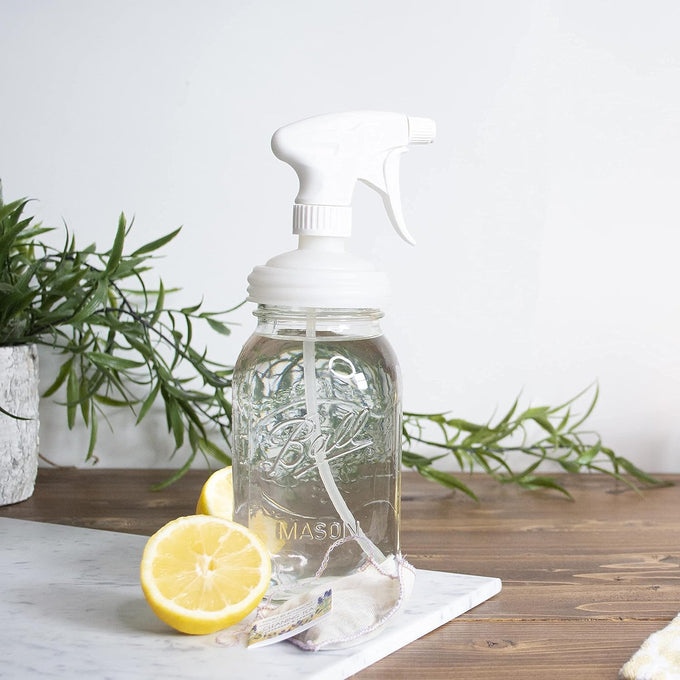 Clear glass mason jar with a white plastic sprayer lid, placed on a wooden surface with fresh lemon halves and green leafy decor, fitting Home & Decor and Household Helpers collections.