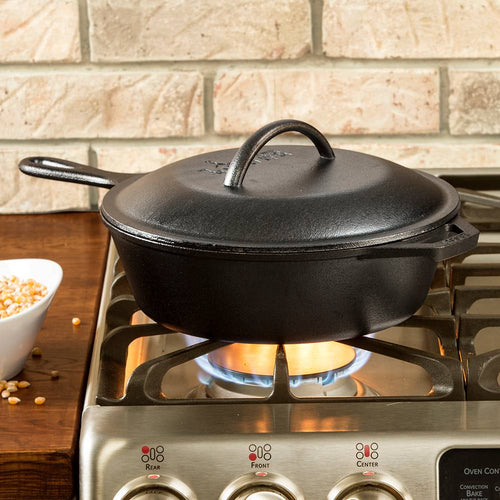 Deep cast iron chicken fryer with lid featuring self-basting nubs, pre-seasoned and designed for even heating, shown on a gas stove in a kitchen setting.
