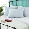 Set of blue and white striped down pillows arranged on a bed with white quilt, featuring an iron headboard and books on the side table, fitting Home & Decor, Home Textiles, Best Sellers, and Promo Eligible collections.