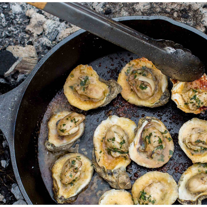 Black pre-seasoned cast iron skillet cooking seasoned oysters over an open flame, highlighting exceptional heat retention and durability for Kitchen & Food, Cookware, Cast Iron, Best Sellers, and Promo Eligible collections.