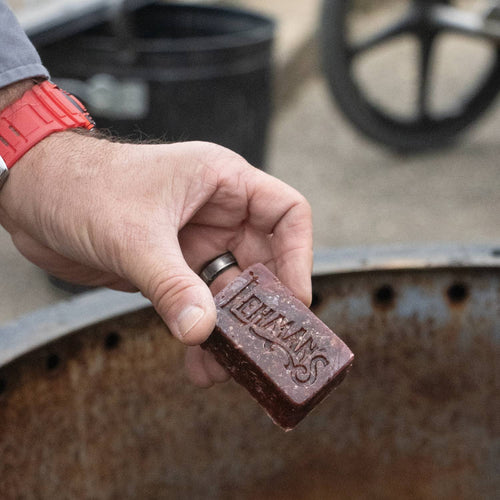 Handcrafted reddish-brown fire starter block embossed with Lehman’s logo, made in the USA from reclaimed wax and sawdust, perfect for Farm, Garden & Tool, Stoves, Camping, and Hearth Accessories.