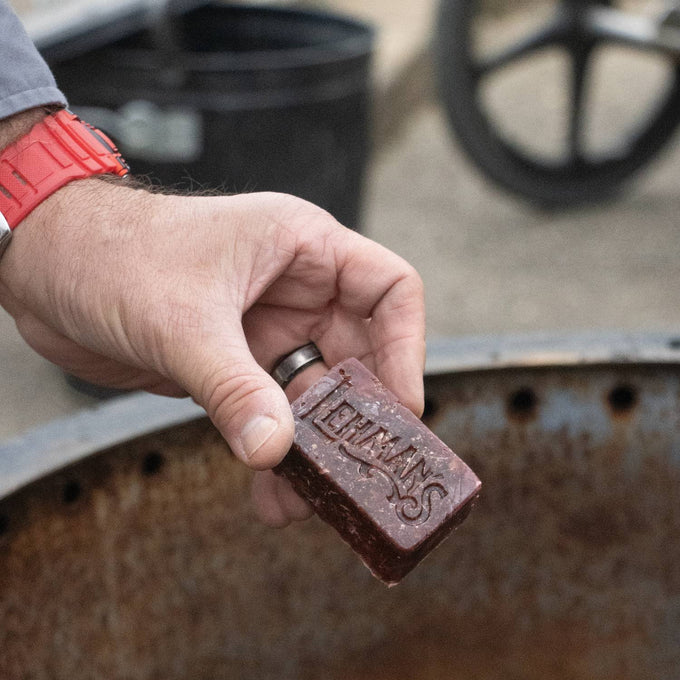 Handcrafted reddish-brown fire starter block embossed with Lehman’s logo, made in the USA from reclaimed wax and sawdust, perfect for Farm, Garden & Tool, Stoves, Camping, and Hearth Accessories.
