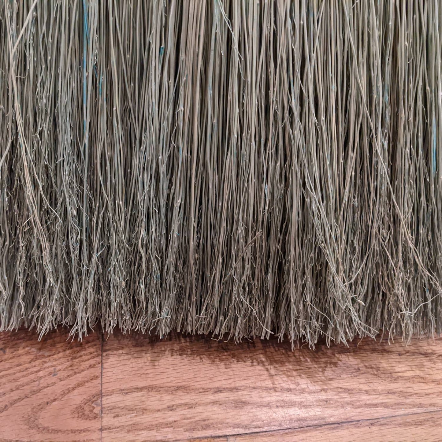 Close-up view of tightly hand-bound natural corn straw bristles on a large Amish made broom, ideal for farmhouse and household cleaning tasks, crafted in the USA.