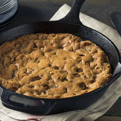 Handcrafted chocolate chip cookie baked in a black 6-inch cast iron skillet, styled on a rustic cloth, ideal for Kitchen & Food, Food, Dry Goods and Mixes, Best Sellers, Promo Eligible collections.