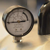 Close-up of a handcrafted pressure gauge displaying temperature and pressure readings on a stainless steel surface, part of Kitchen & Food, Food Preservation, and Pressure Canners collections.