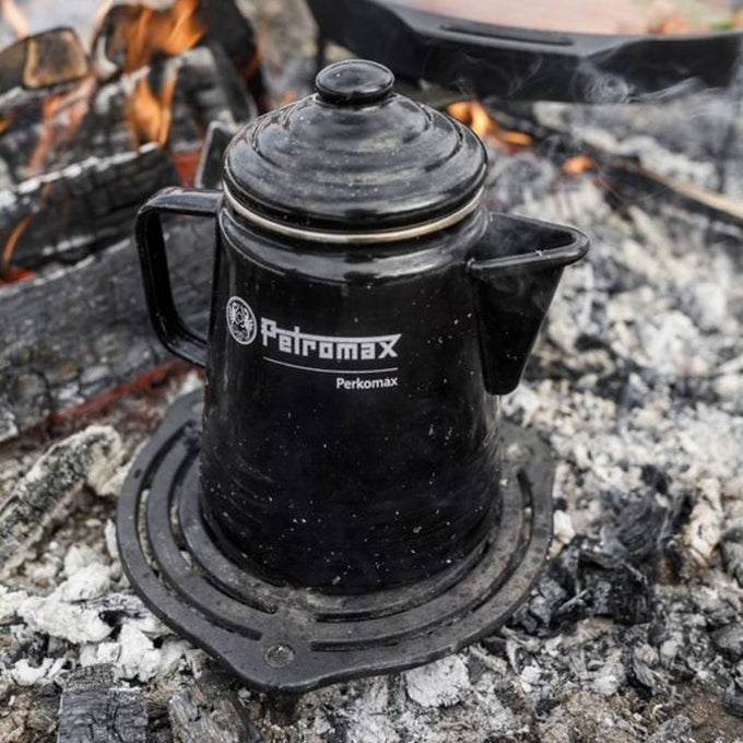 Black enameled steel percolator on a campfire grate with glowing embers, perfect for brewing coffee or tea while camping, featured in Farm, Garden & Tool, Kitchen & Food, and Brewing Coffee and Tea collections.