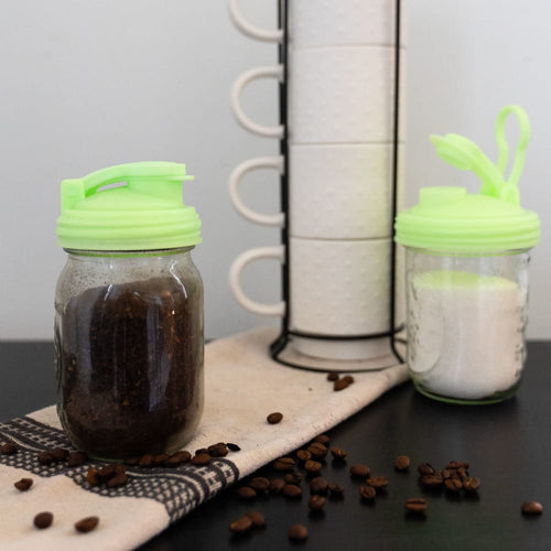 Light green pour lids with flip-top spouts and carry loops fitted on regular-mouth jars, filled with coffee grounds and sugar, made in the USA, ideal for Kitchen Gadgets and USA Made collections.
