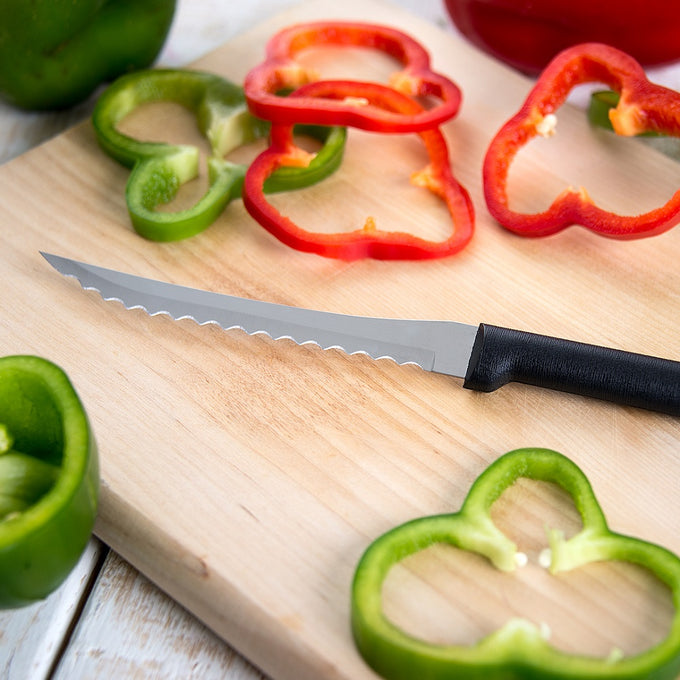 Handcrafted tomato slicer with hand-sharpened high carbon surgical stainless steel serrated blade and black solid handle slicing red and green bell peppers on a wooden cutting board, made in USA, ideal for Farm, Garden & Tool and Kitchen & Food collections.