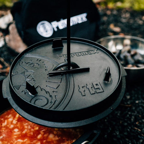 Close-up of a sturdy cast iron lid with embossed design and handle tool lifting it from a pot simmering richly colored stew, perfect for Kitchen & Food, Cookware, Cast Iron, Best Sellers collections.