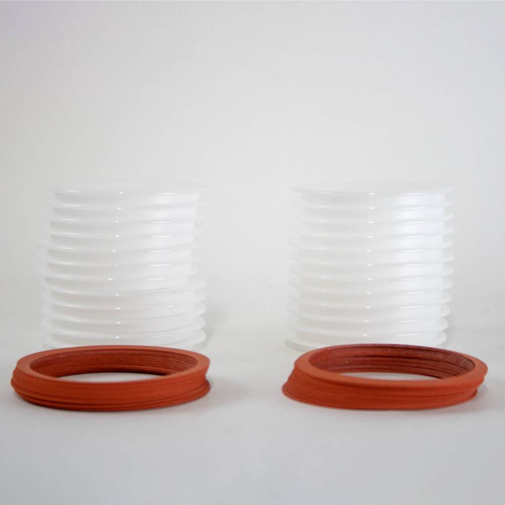 Two stacks of translucent wide-mouth reusable canning jar lids paired with orange sealing rings, ideal for kitchen food preservation in USA made and best sellers collections.