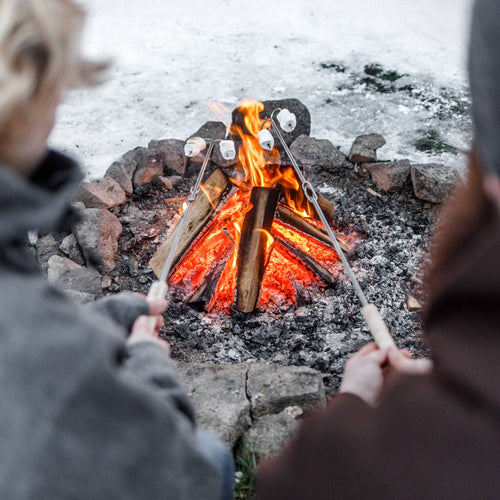 Handcrafted adjustable campfire skewers with natural wooden handles roasting marshmallows over glowing embers in a stone fire pit, perfect for Farm, Garden & Tool, Camping, Best Sellers, and Promo Eligible collections.