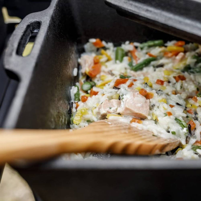 Black cast iron loaf pan with lid, used for cooking hearty rice dish with vegetables and meat, ideal for farm, garden, kitchen, camping, cookware, and cast iron collections.