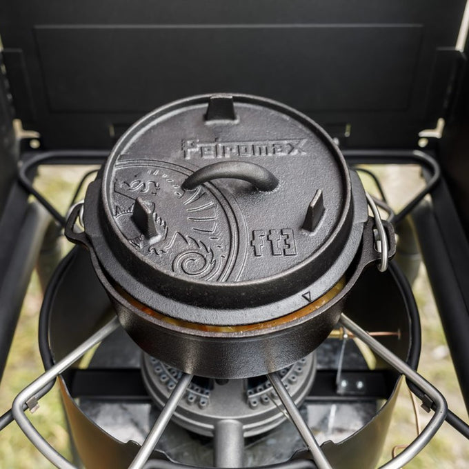Black cast iron Dutch oven with raised legs and an embossed lid featuring a decorative sun pattern and handle, crafted for durable cooking in Kitchen & Food, Cookware, Cast Iron, Best Sellers, and Promo Eligible collections.