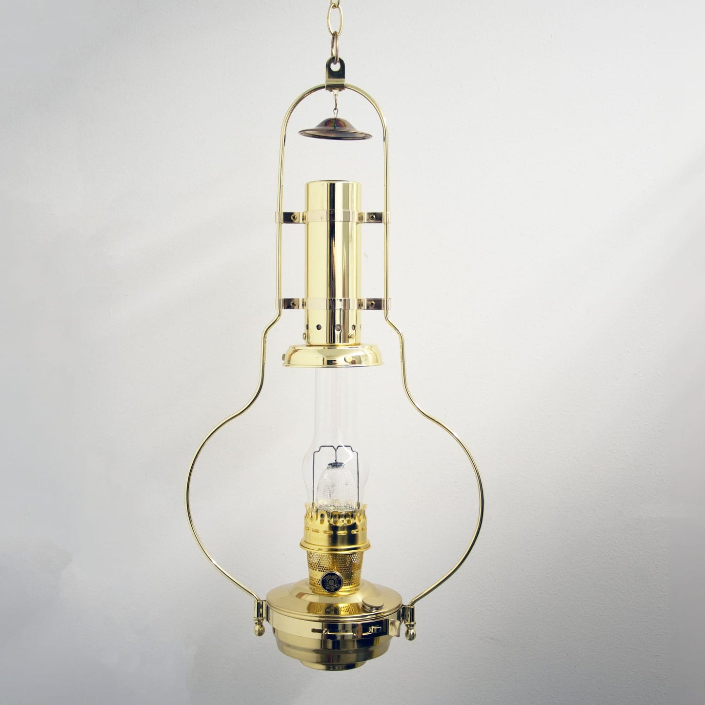 Polished brass hanging oil lamp with a clear glass chimney and solid brass frame, designed to spread warm light, suitable for farm, garden, emergency, and hanging lamp collections.