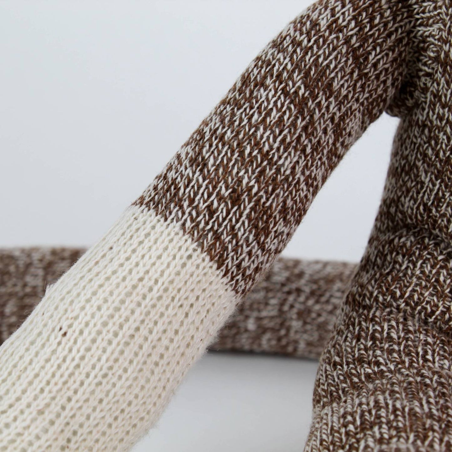 Close-up of a handcrafted arm on a brown and cream knit sock monkey made in USA, featured in Toys, Books & Games, Children's Toys, Indoor Play, and Best Sellers collections.