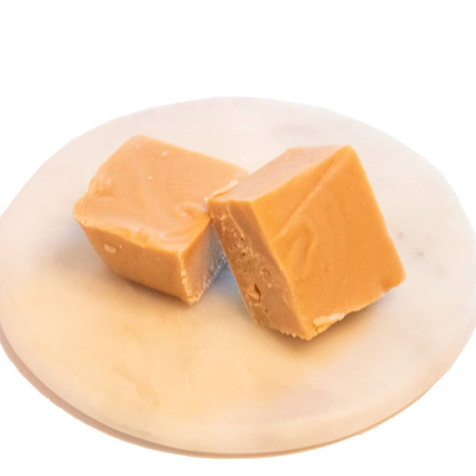 Two handcrafted creamy caramel-colored fudge pieces with a smooth, melt-in-your-mouth texture on a white marble plate, featured in Kitchen & Food, Snacks and Sweets, USA Made, Best Sellers, and Promo Eligible collections.
