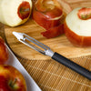 Handcrafted vegetable peeler with razor-sharp stainless steel blade and black resin handle peeling apples on a wooden cutting board, ideal for Kitchen & Food, Specialty Equipment, Peelers and Pitters, USA Made, Best Sellers, Promo Eligible collections.