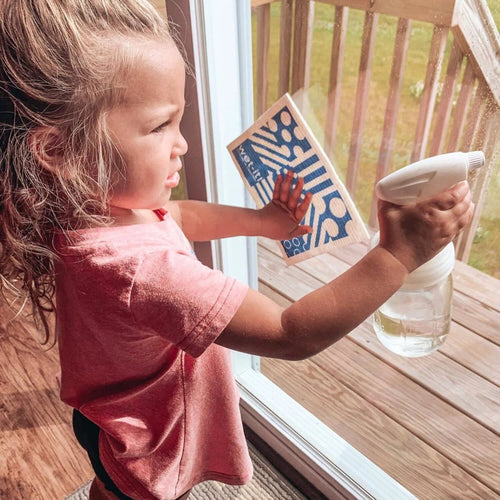 Young child holding a glass jar with a white sprayer lid while cleaning a window, highlighting eco-friendly home cleaning tools from Home & Decor, Household Helpers, USA Made collections.