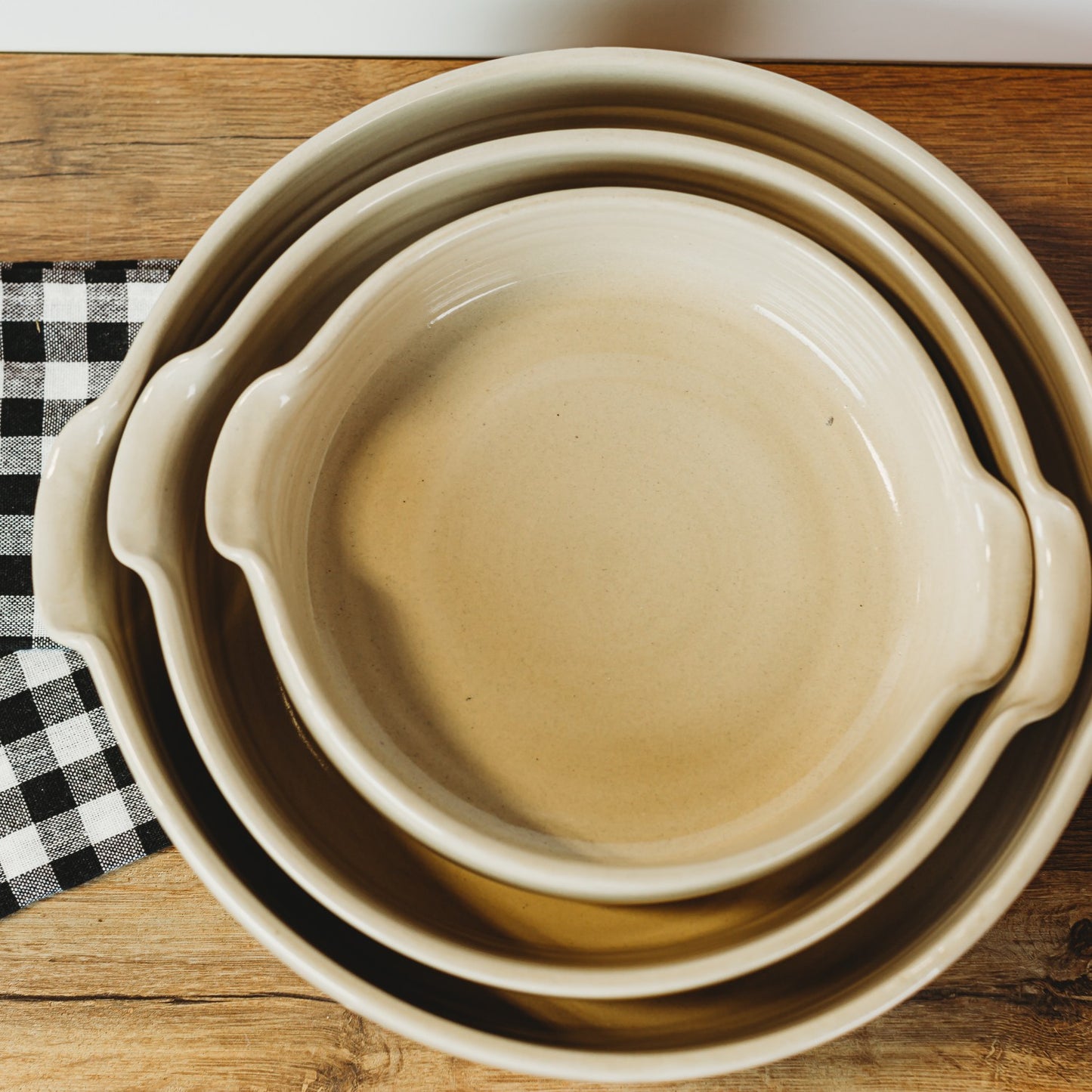 Set of nested beige stoneware bowls with handles, handcrafted in the USA, suitable for Kitchen & Food, Dinnerware, and Storage and Serving collections.