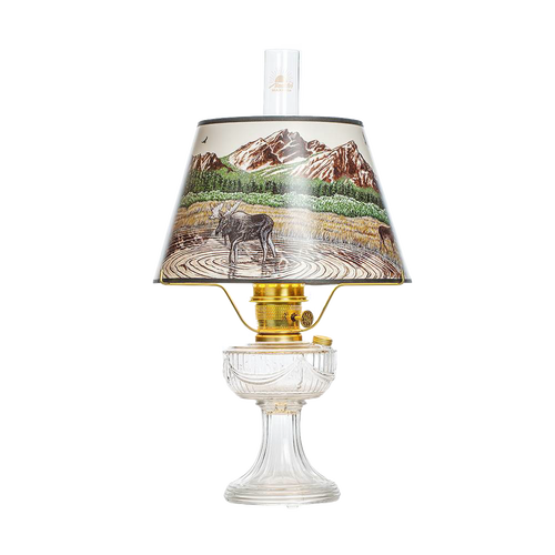 Clear oil lamp with brass burner and a Rocky Mountain scenic parchment shade depicting a moose by a lake with mountains in the background, featured in Lamps & Lighting, Oil Lamps, Table Lamps, Best Sellers, and Promo Eligible collections.