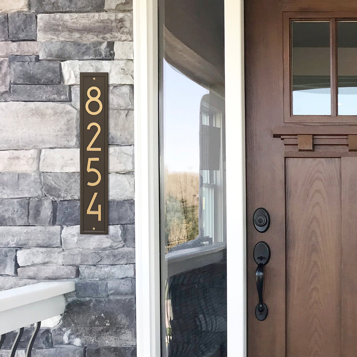 Handcrafted vertical aged bronze address plaque with contemporary numbers mounted on stone siding, enhancing curb appeal, made in USA, featured in Home & Decor and Mailboxes and Address Signs collections.