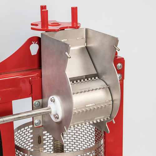 Close-up of a stainless steel fruit crusher with sharp blades mounted on a sturdy red frame, designed for hygienic apple processing in farm and orchard settings.