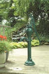 Green cast iron hand water pump mounted on wooden deck near garden with foliage and a small rock waterfall, featured in Appliances, USA Made, Water Pumps, Deep Well Pumps, Best Sellers, and Promo Eligible collections.