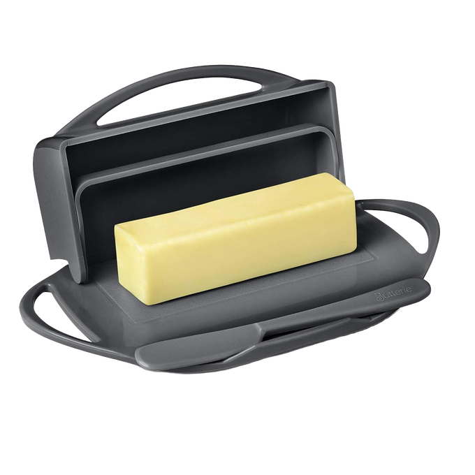 Dark gray flip-top butter dish holding a rectangular block of soft butter with a matching spreader resting on a built-in cradle, crafted for easy use and mess-free storage in Kitchen & Food and Kitchen Gadgets collections.