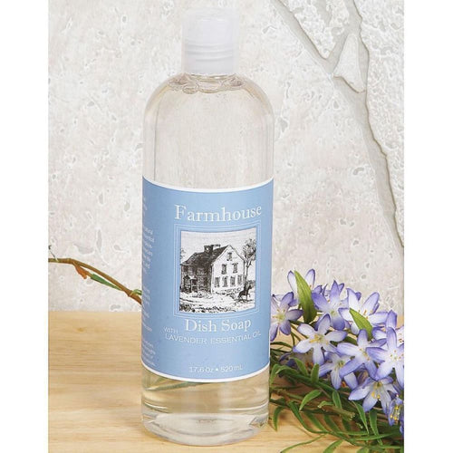 Clear bottle of handcrafted farmhouse dish soap with lavender essential oil label, placed on wooden surface next to purple flowers, featured in Home & Decor and USA Made collections.