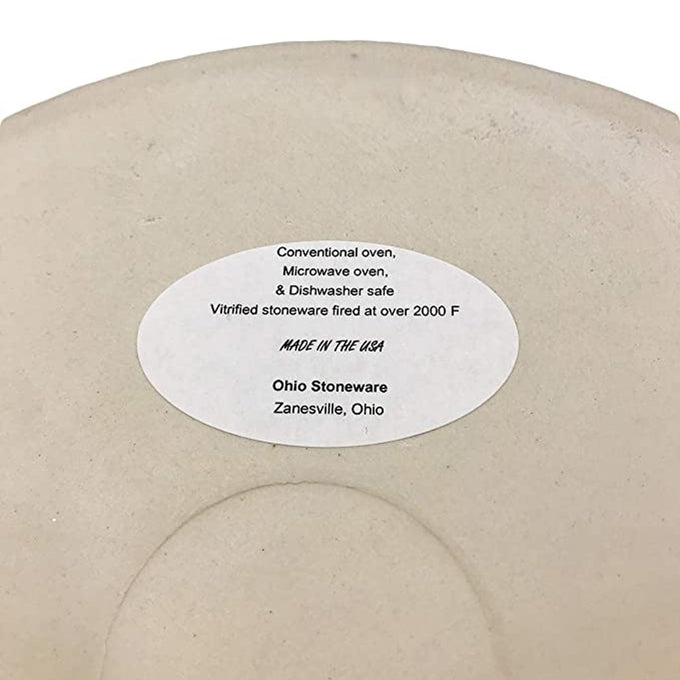 Close-up of the bottom of a handcrafted cream-colored stoneware crock with an oval label stating it is made in Zanesville, Ohio, USA, oven and dishwasher safe, part of Kitchen & Food and Food Preservation collections.