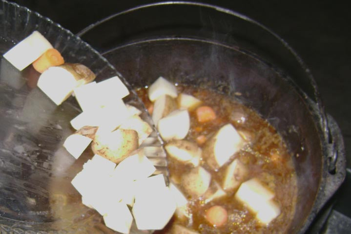 Veggies in stew Adding chopped veggies to stew.