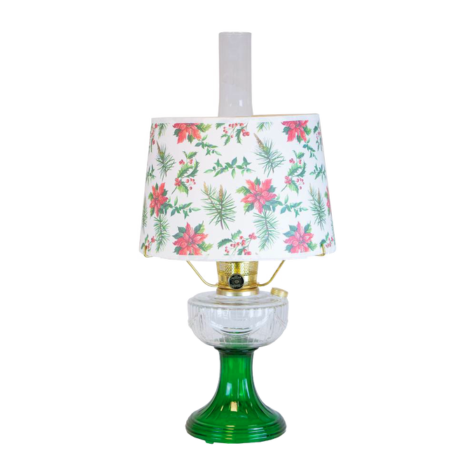 Handcrafted oil table lamp with clear over emerald glass base and festive parchment shade decorated with red poinsettias and green holly, featured in Lamps & Lighting and Best Sellers collections.