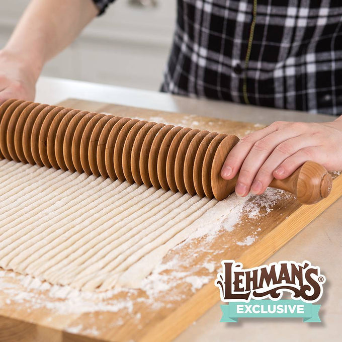 Handcrafted Amish-made unfinished cherry wood noodle cutter with multiple wheels cutting evenly spaced 3/8-inch noodles on floured wooden board, ideal for Kitchen & Food and Food Prep collections.