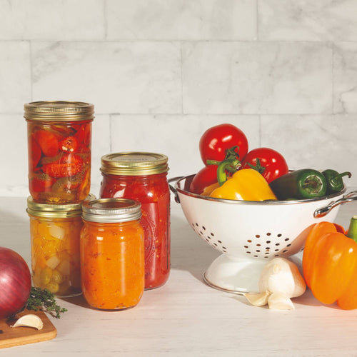 Set of twelve wide-mouth canning lids and bands with BluSeal™ adhesive made in USA, displayed with fresh vegetables and preserved jars, ideal for Kitchen & Food and Food Preservation collections.