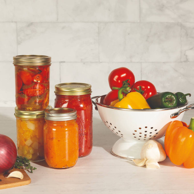 Set of twelve wide-mouth canning lids and bands with BluSeal™ adhesive made in USA, displayed with fresh vegetables and preserved jars, ideal for Kitchen & Food and Food Preservation collections.