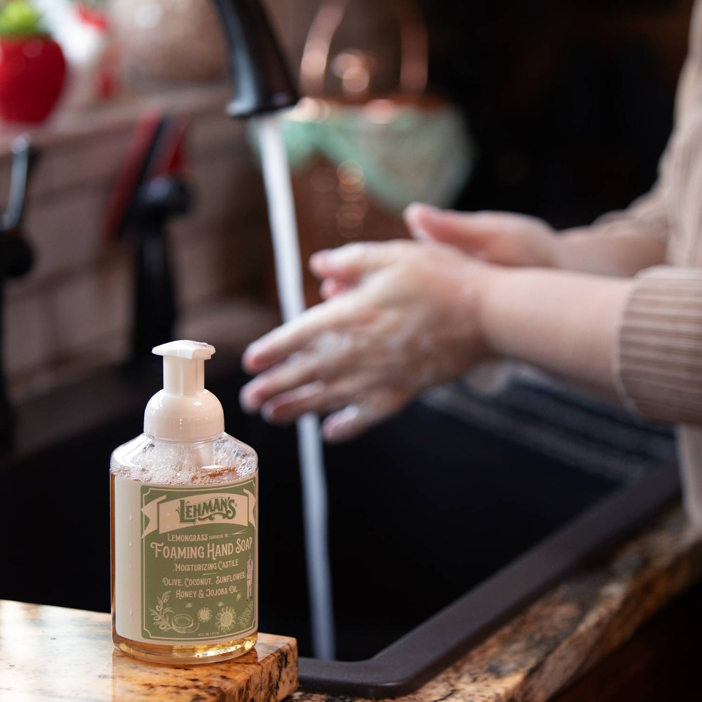 Lehman's Castile foaming hand soap bottle on kitchen counter with hands being washed under running water, natural moisturizing formula for Health & Wellness and Grooming collections