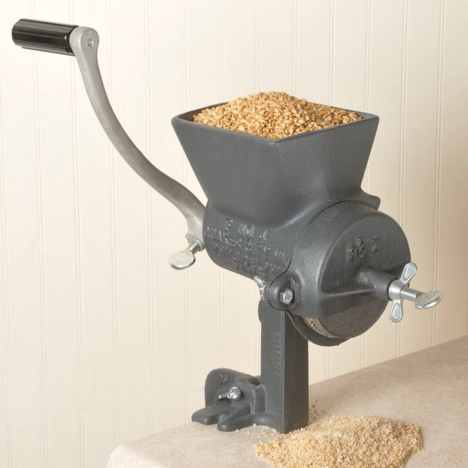 Heavy-duty hand-cranked grain mill with a large hopper filled with dry grains, sturdy cast iron construction, and secure clamp base, crafted for Kitchen & Food, Grain Mills, and USA Made collections.