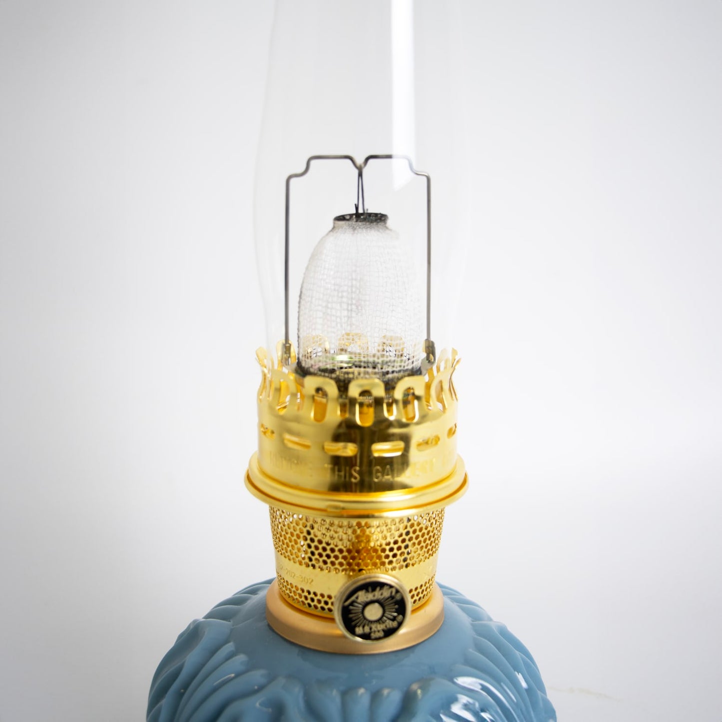 Close-up of a handcrafted limited edition oil lamp with a glossy blue glass base and detailed brass burner, featured in Lamps & Lighting, Oil Lamps, Table Lamps, Best Sellers, and Promo Eligible collections.
