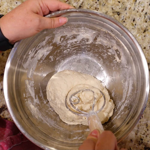 Handcrafted Amish made dough whisk with two spiral metal wires and a smooth wooden handle mixing dough in a stainless steel bowl, ideal for Kitchen & Food, Baking Supplies, and USA Made collections.