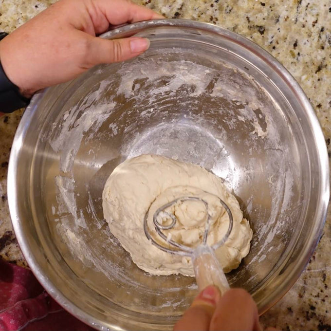 Handcrafted Amish made dough whisk with two spiral metal wires and a smooth wooden handle mixing dough in a stainless steel bowl, ideal for Kitchen & Food, Baking Supplies, and USA Made collections.